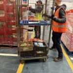 image shows man pushing a cage loaded with sprouts in the warehouse