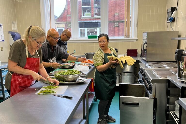 Tameside Meals Project. Image shows 4 members of Tameside Meals Project preparing food in a commercial kitchen