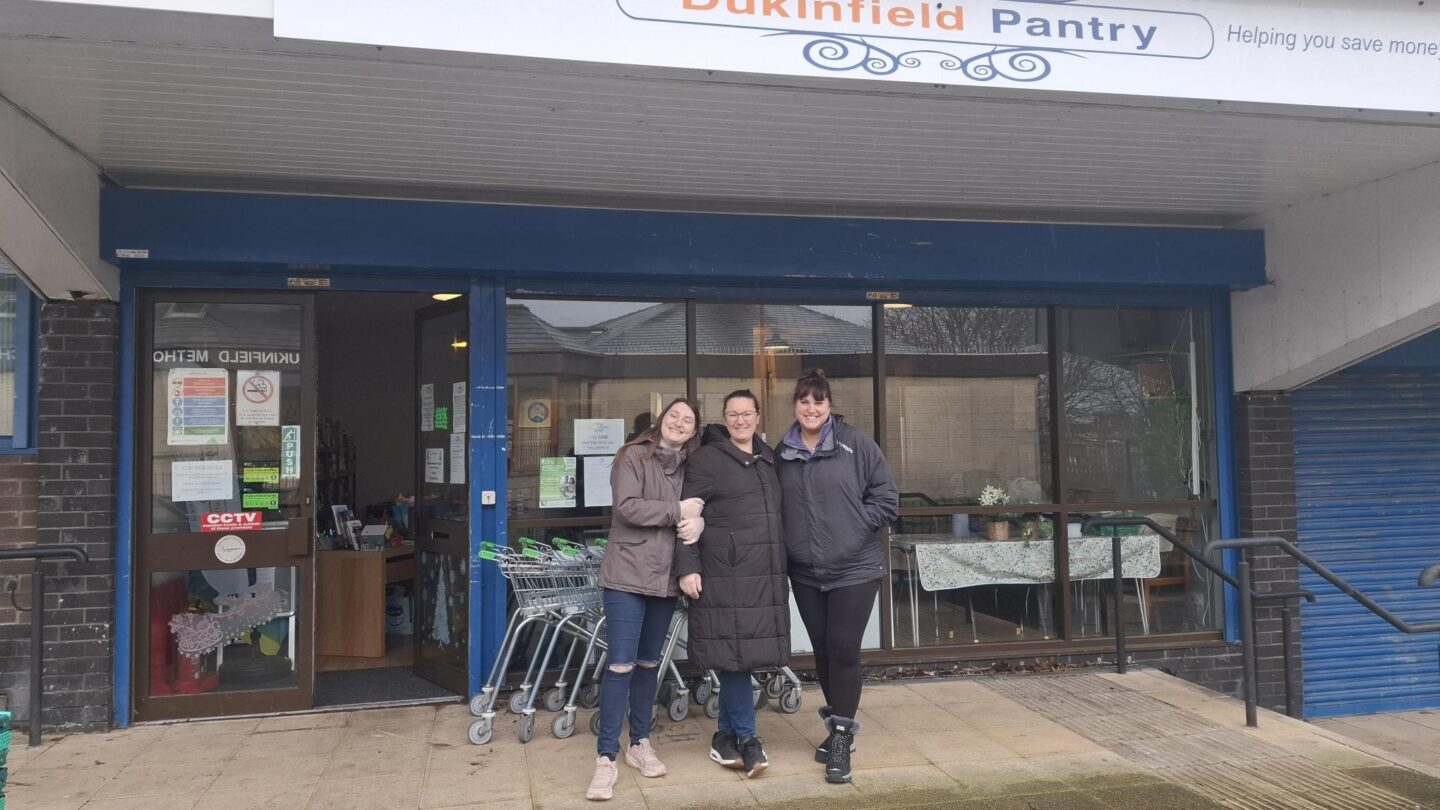 Image shows three volunteers from Dukinfield Pantry standing outside the front of the building