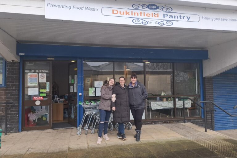 Image shows three volunteers from Dukinfield Pantry standing outside the front of the building